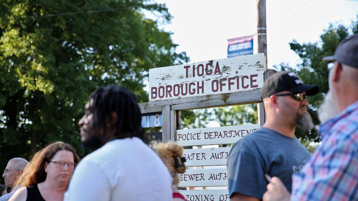 People stand in front of the sign for Tioga borough’s office.