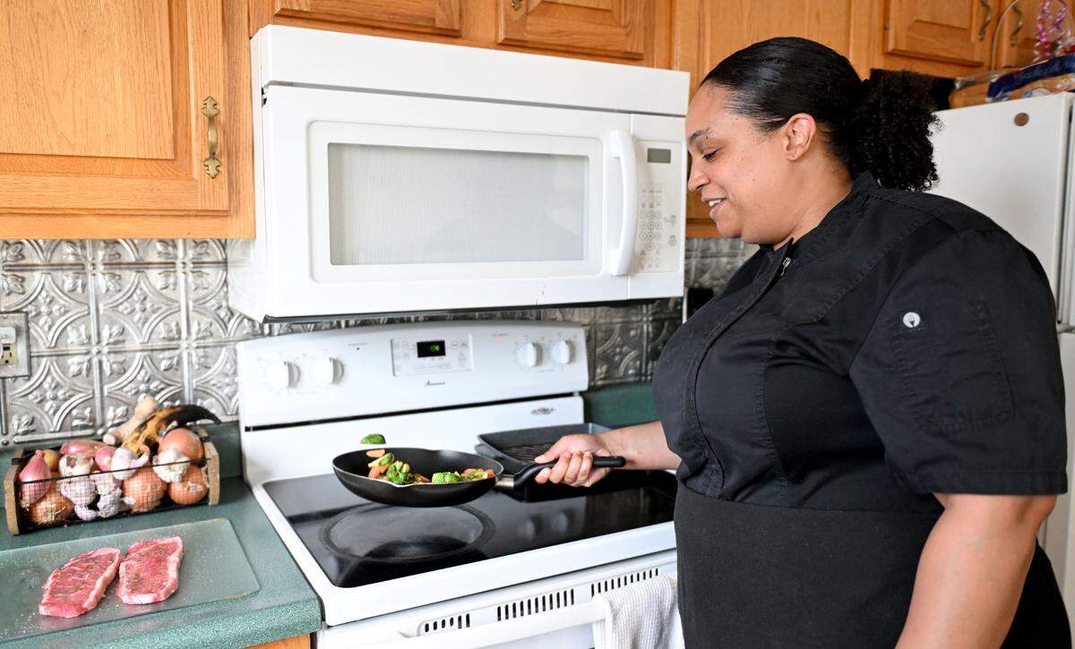 Chef Shavonne Hart tosses carrots and Brussels sprouts on Thursday, June 26, 2025.