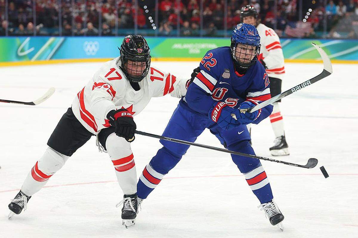 MILAN, ITALY - FEBRUARY 19: Ella Shelton #17 of Team Canada and Tessa Janecke #22 of Team United States skate after the puck in the second period during the Women's Gold Medal match between the United States and Canada on day 13 of the Milano Cortina 2026 Winter Olympic games at Milano Santagiulia Ice Hockey Arena on February 19, 2026 in Milan, Italy. (Photo by Gregory Shamus/Getty Images)