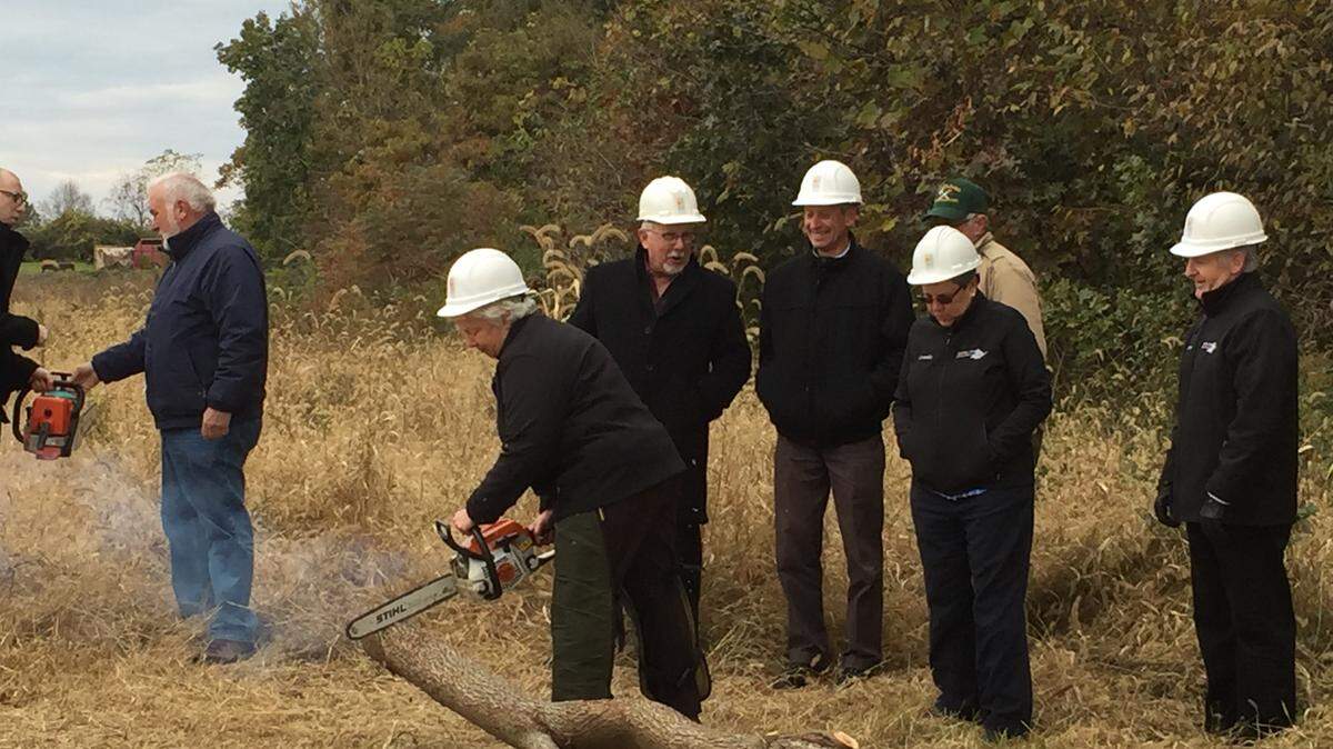 Centre Care Board President Betsy Boyer cuts a tree limb with a chainsaw on Friday, Oct. 26, 2018, to celebrate five years as a nonprofit and the new facility, which will break ground in March.