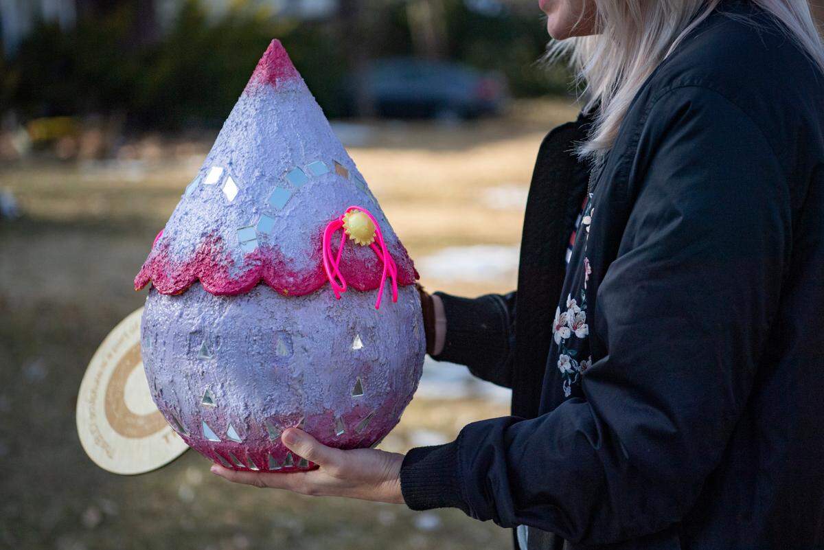 Alex Russell, a graduate student in the Penn State School of Visuals Arts, places her Buds! community art piece in a yard on Monday.