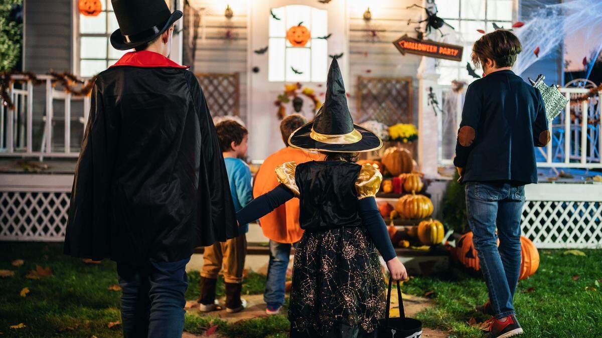 Young kids trick or treating at night during Halloween