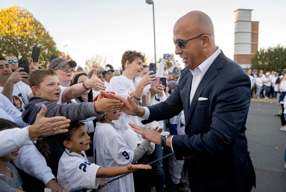 Penn State football coach James Franklin high-fives fans as he and the team arrive at Beaver Stadium for the game against Minnesota on Saturday, Oct. 22, 2022.
