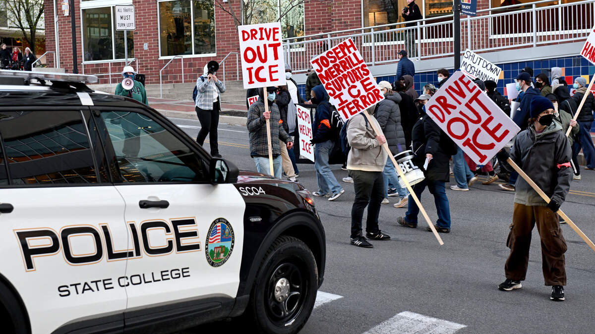 ICE protesters block a State College Police car from turning out of the Fraser Street garage as they march up the street on Monday, April 20, 2026.
