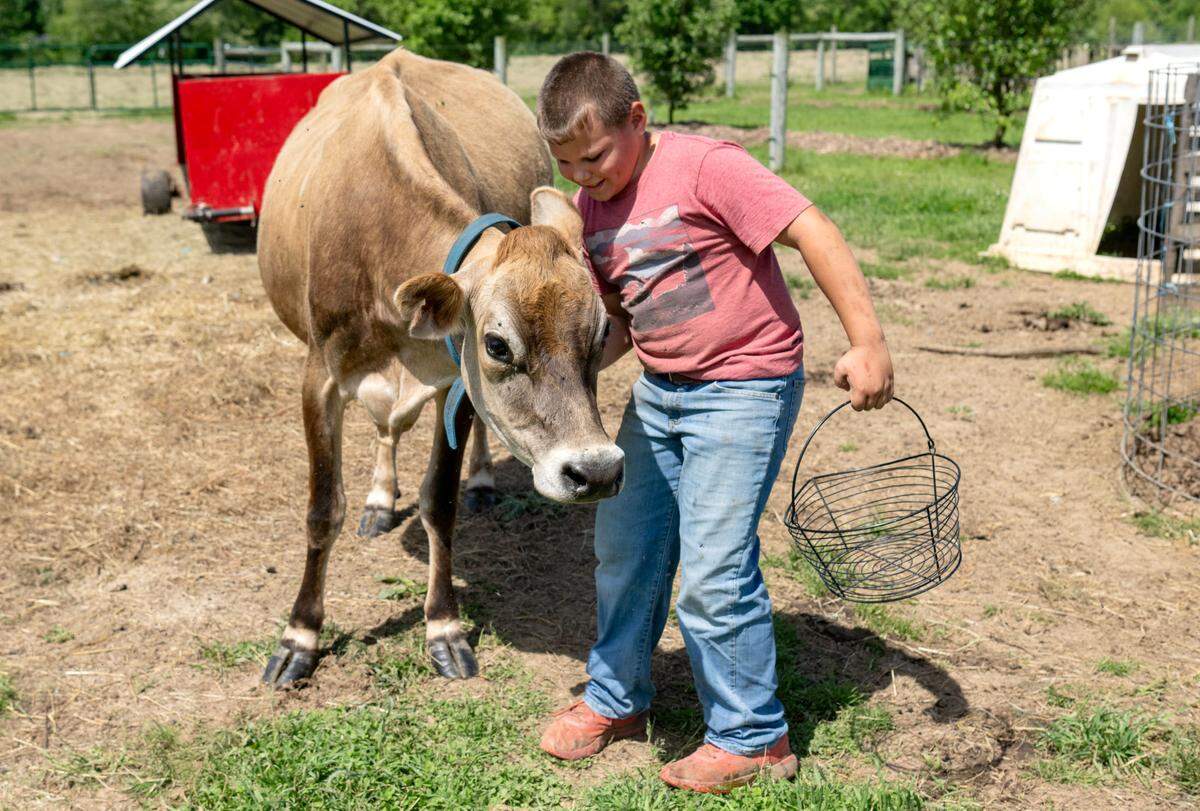 Jadon King, 10, gives some neck scratches to Twinkle as he heads out to collect eggs at Stem to Stable Farm in Centre Hall on Tuesday, May 21, 2024.