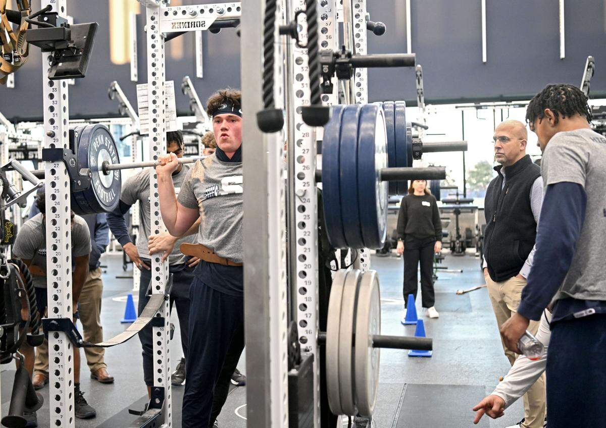 Penn State quarterback Drew Allar lifts as coach James Franklin stands off to the side to watch during a winter workout session on Thursday, Feb. 29, 2024.
