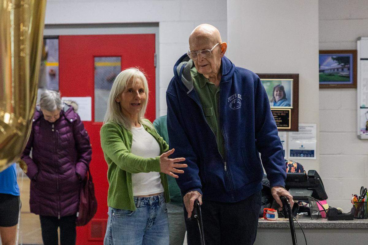 Fellow swimmer Heidi Wright, left, gives a heart-warming speech for Maynard Kohler, right, during his 100th birthday party at the YMCA in State College on Friday, Jan. 23, 2026. 