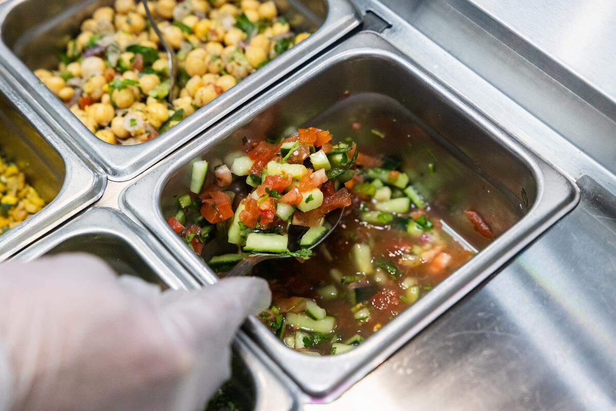 Mohammad Hayajnehon scoops up some tomato cucumber salad as he makes a Beirut bowl in Fava Kitchen on Sunday, Feb. 8, 2026 in State College.