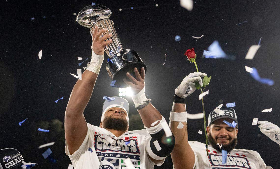 Penn State defensive tackle PJ Mustipher holds up the Leishman Trophy as he and the team celebrate their Rose Bowl win over Utah.
