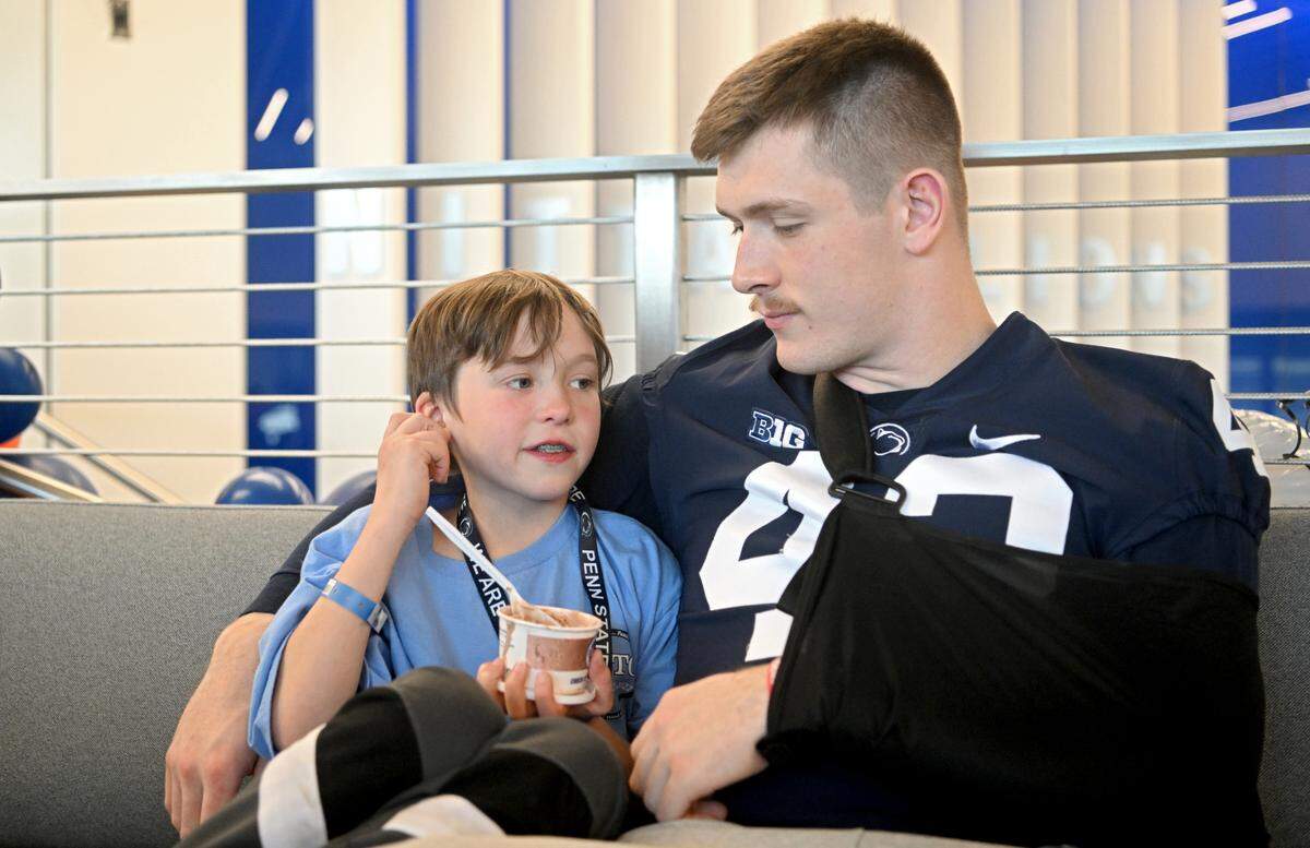 Mathias Tramel, 9, talks to Penn State linebacker Tyler Elsdon about his pets as he enjoys some ice cream during the Thon Explorers program at the Lasch Building on Saturday, Feb. 18, 2023.