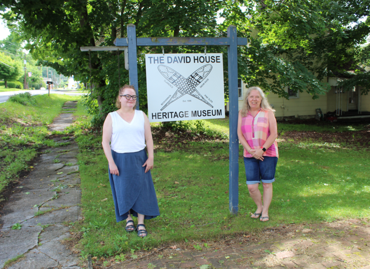 Co-editors and Mountaintop residents Kelly Miller and Lori Hoffman post next to the David House Heritage Museum’s sign.