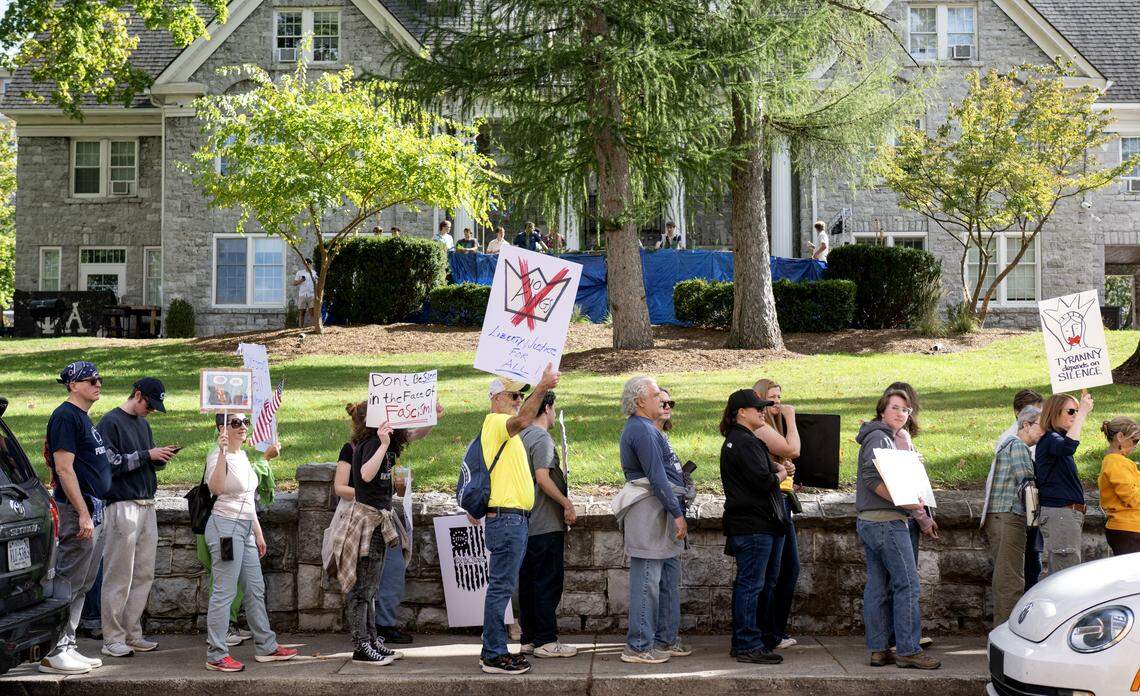 A frat house watches protesters line Beaver Avenue as they wait to cross Pugh Street as part of the No Kings anti-Trump rally on Saturday, Oct. 18, 2025. The march stayed on the sidewalks and only crossed at intersections during red lights.  