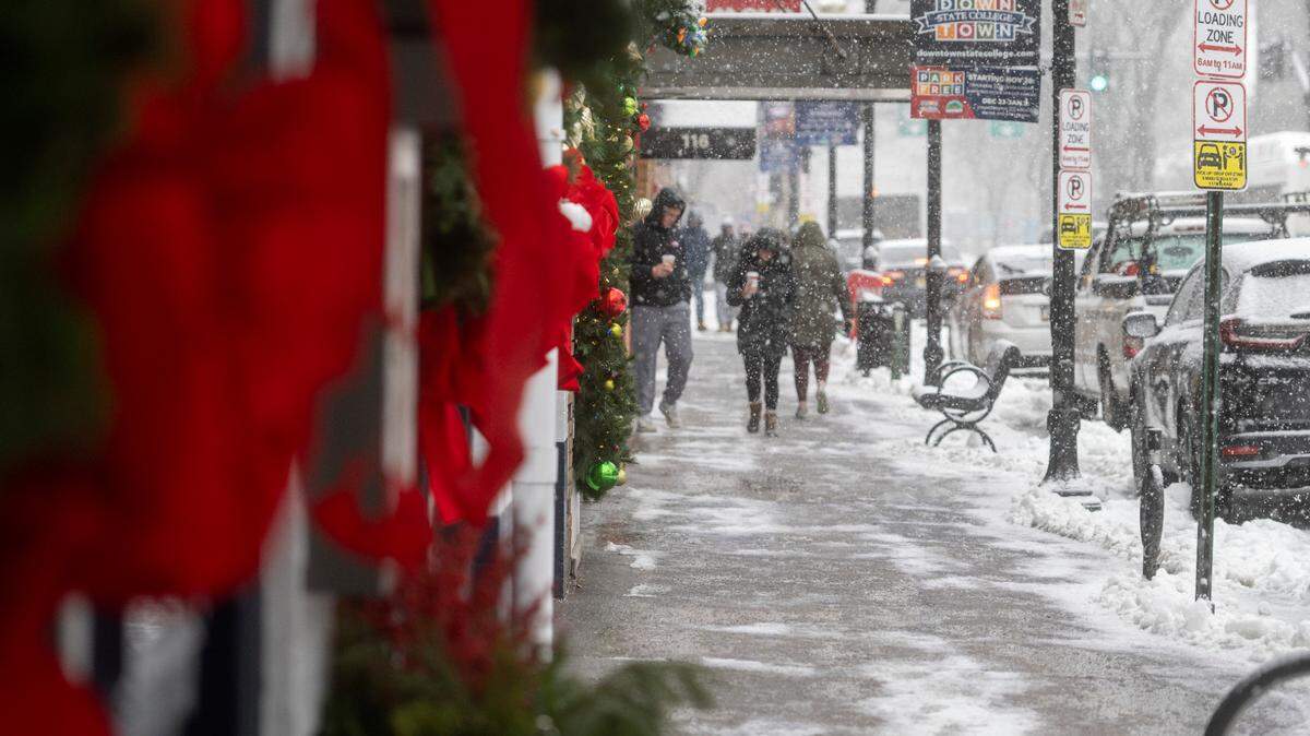 Holiday wreaths hang at Hotel State College as people walk through the snow Thursday, Dec. 15, 2022. Centre County can expect more cold weather just in time for Christmas, according to the National Weather Service.