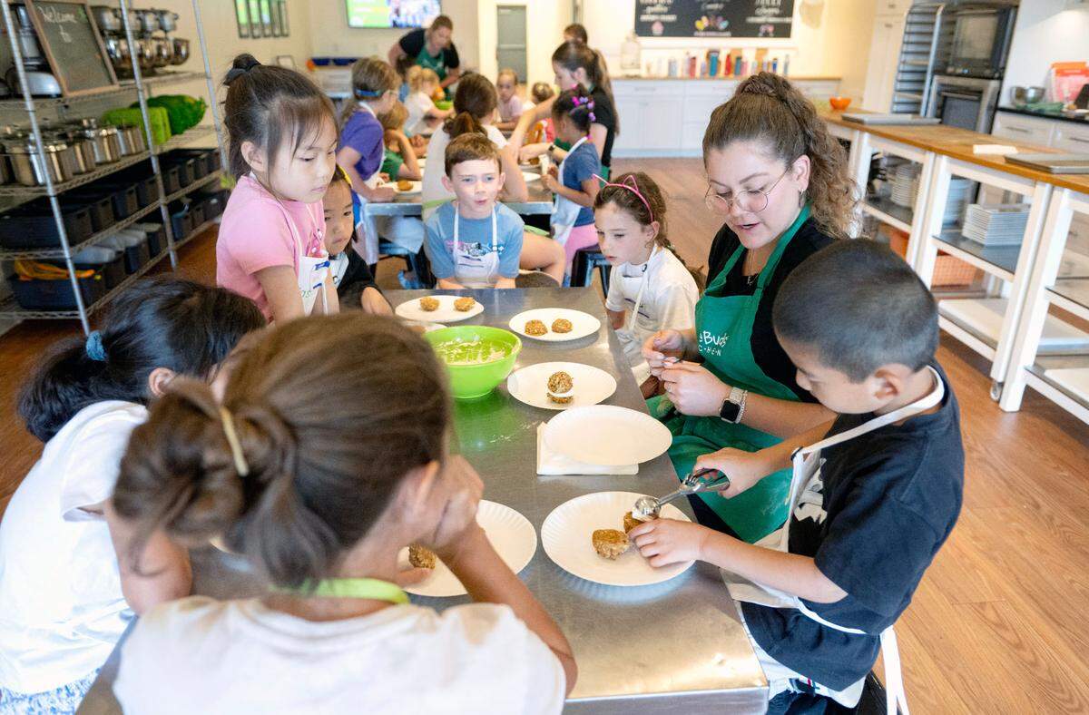 Counselor Isabella Messina helps campers scoop the creme cheese filling for their apple oatmeal cream pies during Taste Buds Kitchen summer camp on Tuesday, July 1, 2025.