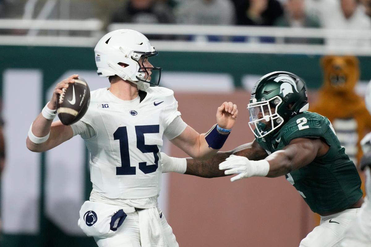 Penn State quarterback Drew Allar (15) is pressured by Michigan State defensive lineman Khris Bogle (2) during the first half of an NCAA college football game, Friday, Nov. 24, 2023, in Detroit.