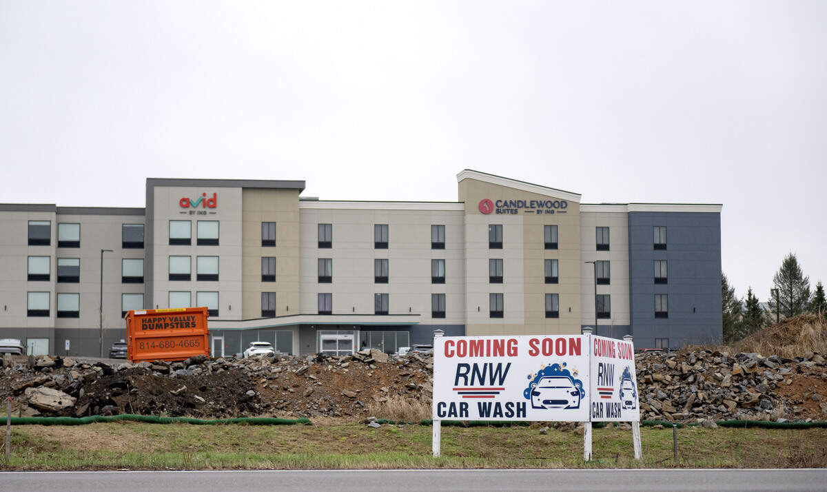 A sign promoting a car wash along Benner Pike in front of the newly opened Candlewood Suites and Avid Hotel on Thursday, April 2, 2026.