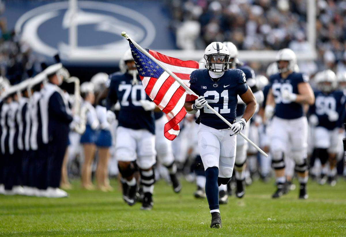 Penn State running back Noah Cain leads the team onto the field with an American flag before the game against Rutgers on Saturday, Nov. 20, 2021. CainÕs father Terence is a veteran.