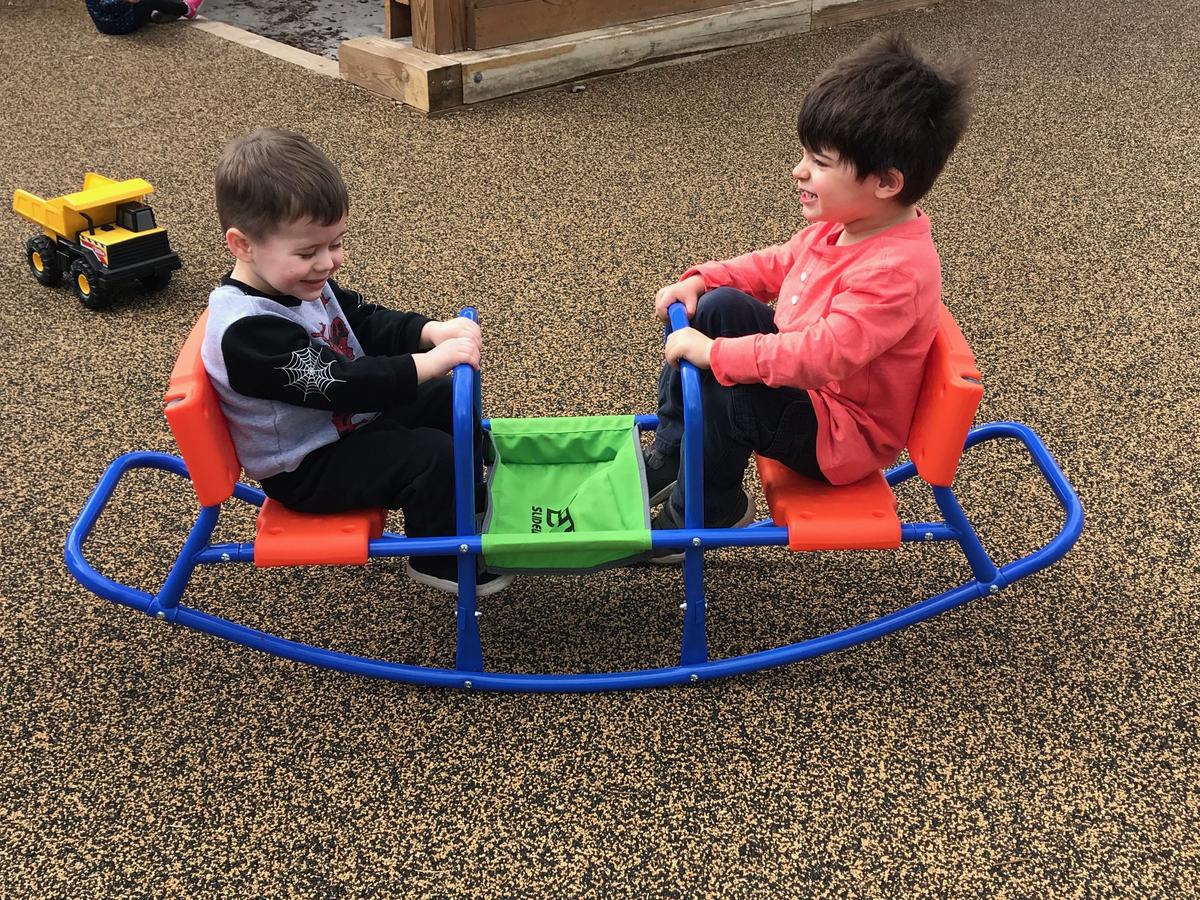 Two children play on the newly surfaced playground at Easterseals.