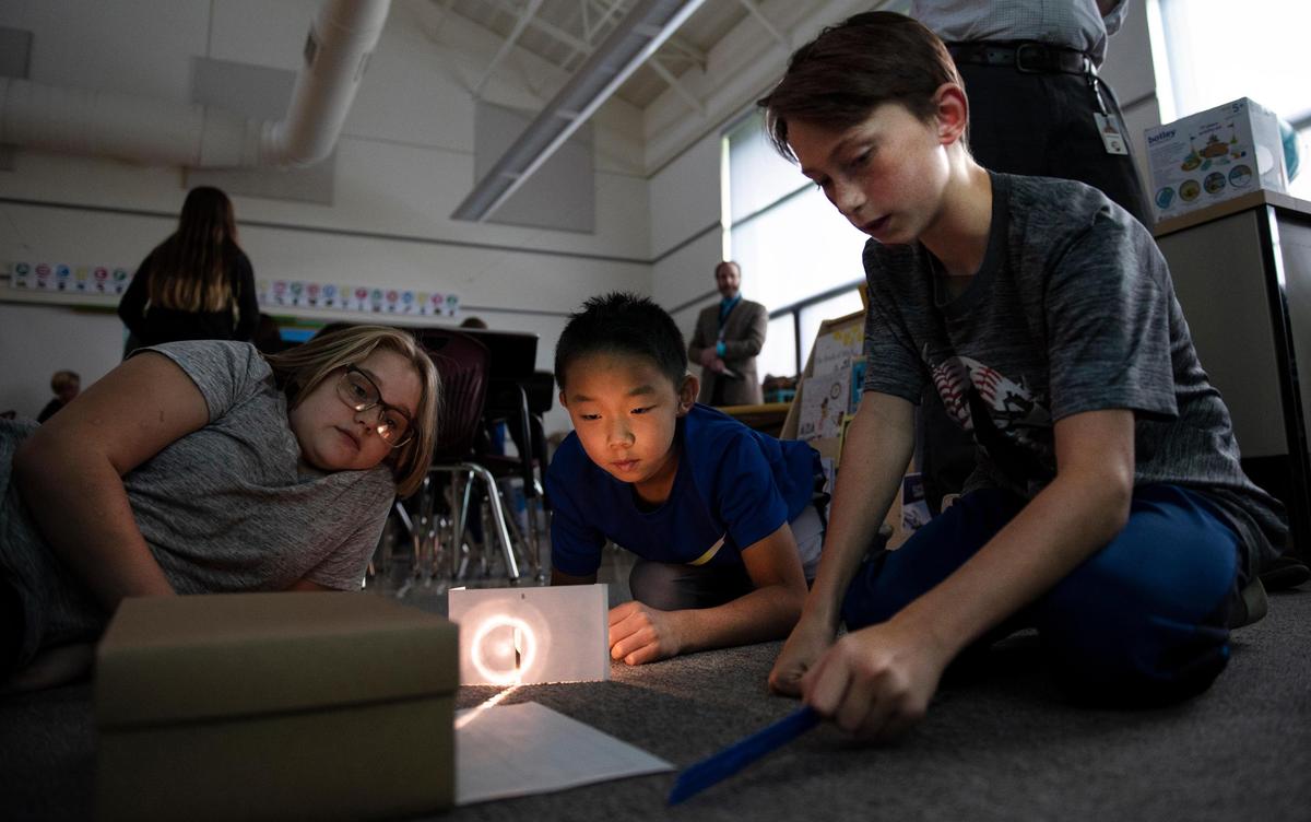 Phoebe Jensen, left, William Liu, middle, and Tiaden Markle, look at the light of a class experiment in the STEM class on Oct. 17, 2018, at Ferguson Township Elementary School in State College, Pa. (Photo/Baidi Wang)