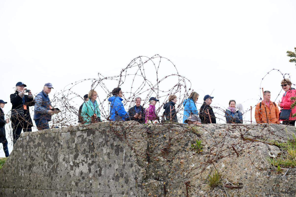 Members of the D-Day: The Invasion of Normandy and the Liberation of France tour sponsored by the Penn State Alumni Association walk across the remains of a German bunker and gun emplacement overlooking Omaha Beach in Normandy, May 18, 2019.