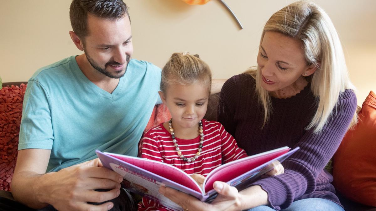 Rooney, 4, reads “Abigail: The Belle of Bravery” with her parents Brent and Erin Weidemann on Wednesday, Nov. 21, 2018.