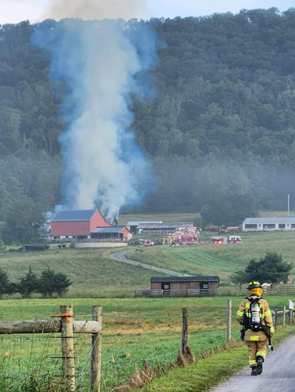 A firefighter walks toward the second-alarm barn fire in Miles Township Monday morning.