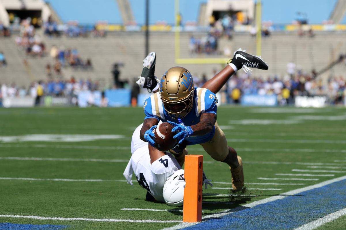 Oct 4, 2025; Pasadena, California, USA;  UCLA Bruins wide receiver Kwazi Gilmer (3) scores a touchdown against Penn State Nittany Lions cornerback AJ Harris (4) during the first quarter at Rose Bowl. Mandatory Credit: Kiyoshi Mio-Imagn Images