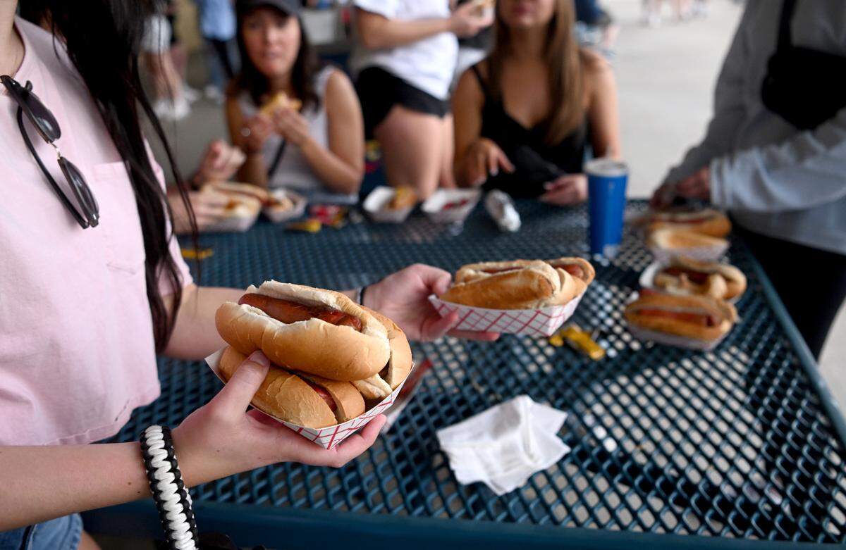 A student carries her hot dogs during dollar dog night at the Penn State baseball game on Tuesday, April 11, 2023 at Medlar Field.