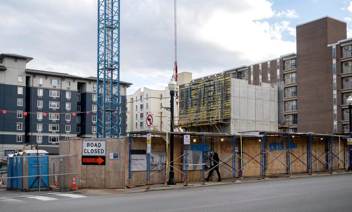 A pedestrian walks by the construction of oLIV State College, a new high-rise on the corner of Hetzel Street and East College Avenue.