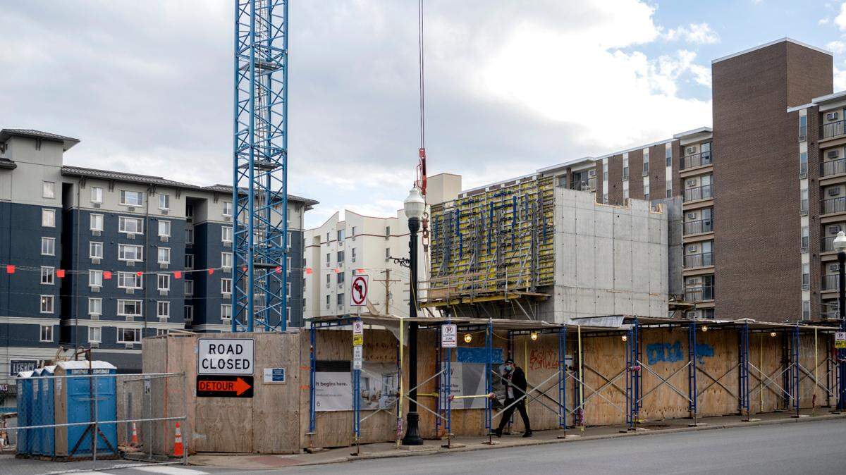 A pedestrian walks by the construction of oLIV State College, a new high-rise on the corner of Hetzel Street and East College Avenue, in October 2022.