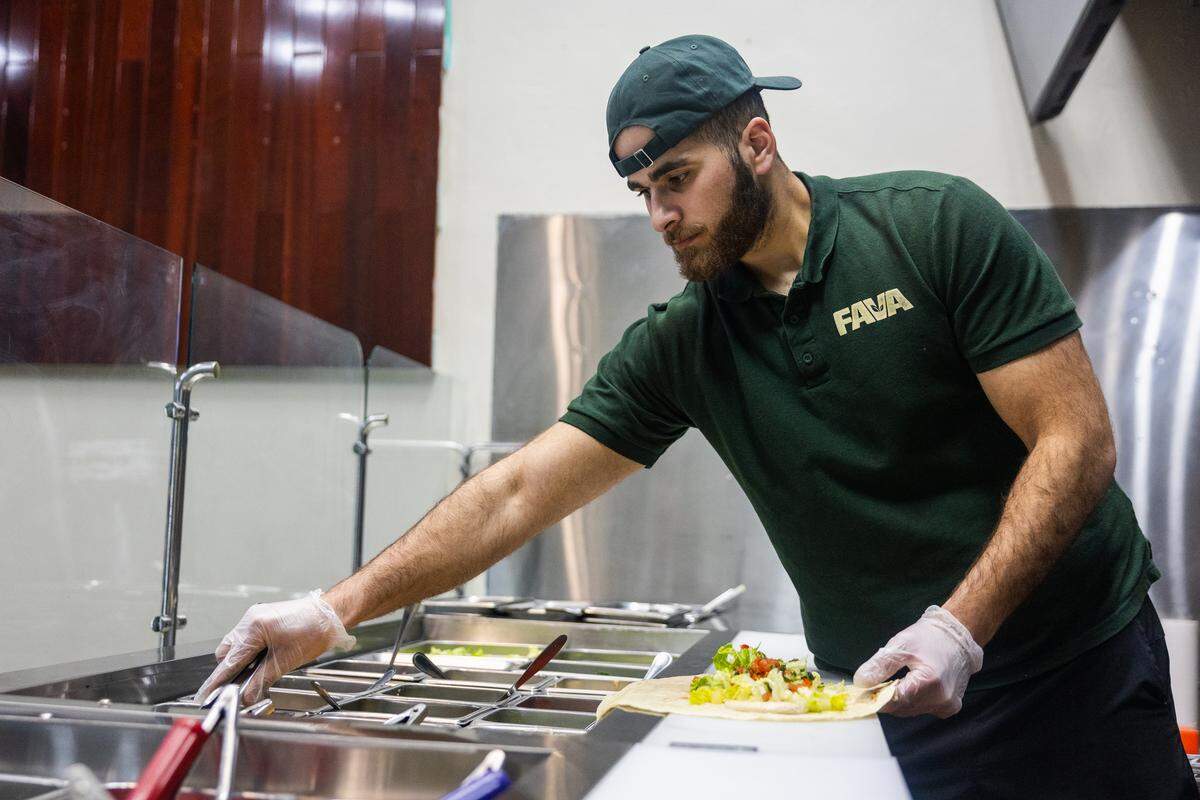 Mohammad Hayajnehon reaches for ingredients as he makes a Beirut bowl in Fava Kitchen on Sunday, Feb. 8, 2026 in State College.