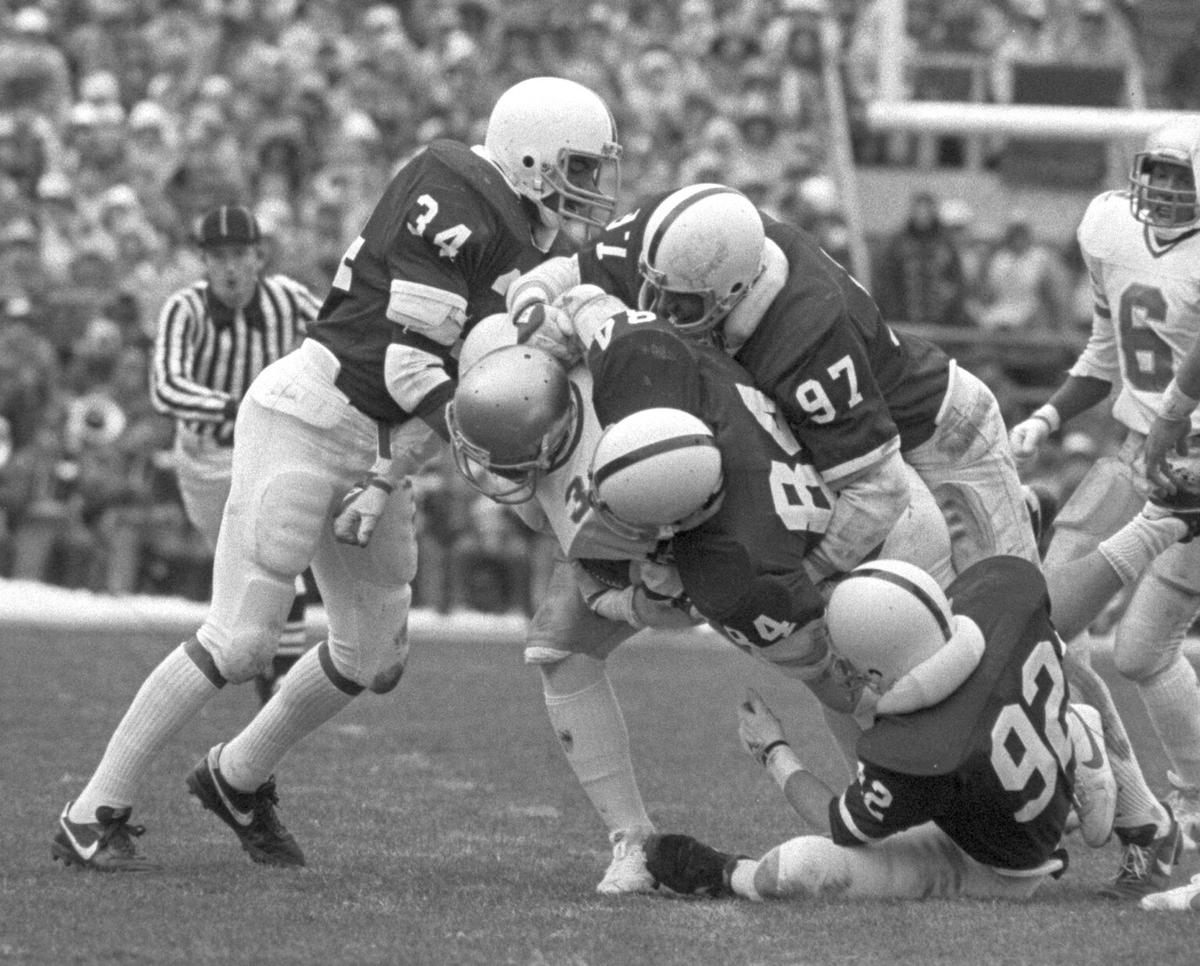 Penn State’s  Bob White (#34); Scott Radecid (#97); Carmen Masciantonio  (#84); and Mark Fruehan (#92) bring down a Notre Dame player during the 34-30  win against Notre Dame at Beaver Stadium on November 12, 1983.
