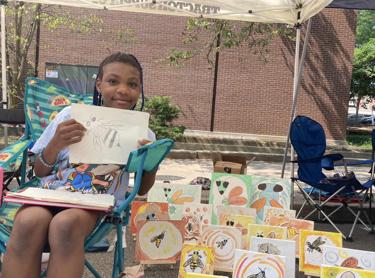 Cydnie Jackson poses with her paintings, and the wasp drawing she was working on today.