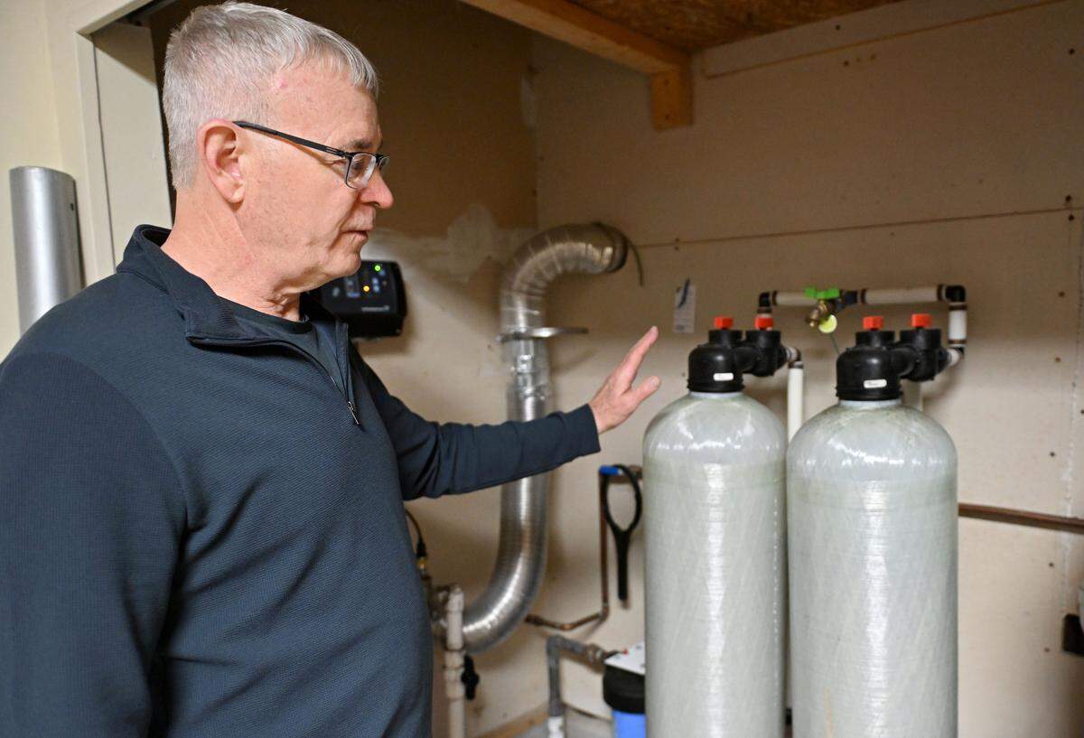 Rick Weyer shows the point-of-entry treatment system he had installed at his home after his well was contaminated by PFAS. 