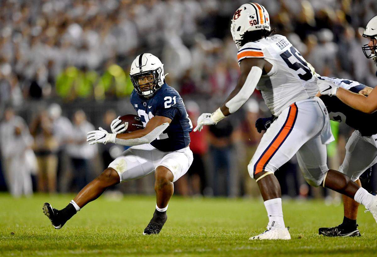 Penn State running back Noah Cain costs down the field with the ball around an Auburn defender during the game.