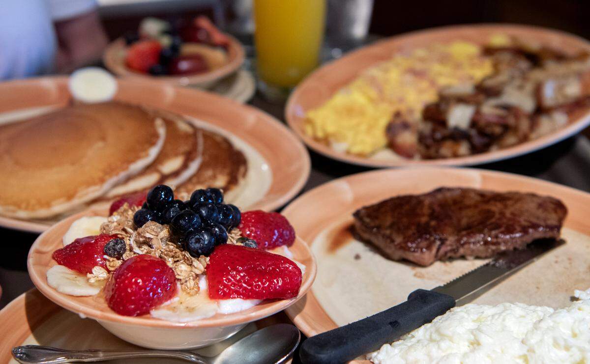 An order including pancakes, a breakfast salad and steak and eggs is delivered to a table at the Original Waffle Shop West on West College Avenue on Wednesday, March 16, 2022.