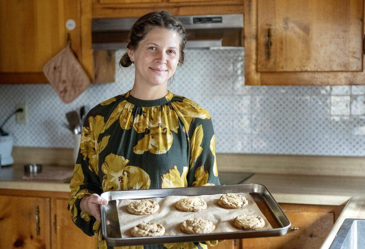 Alyssa Burns of Blackberry Cottage Bake Shoppe holds a fresh out of the oven tray of chocolate chip cookies on Friday, Nov. 14, 2025. The cookies are made with organic einkorn flour and no refined sugars.  