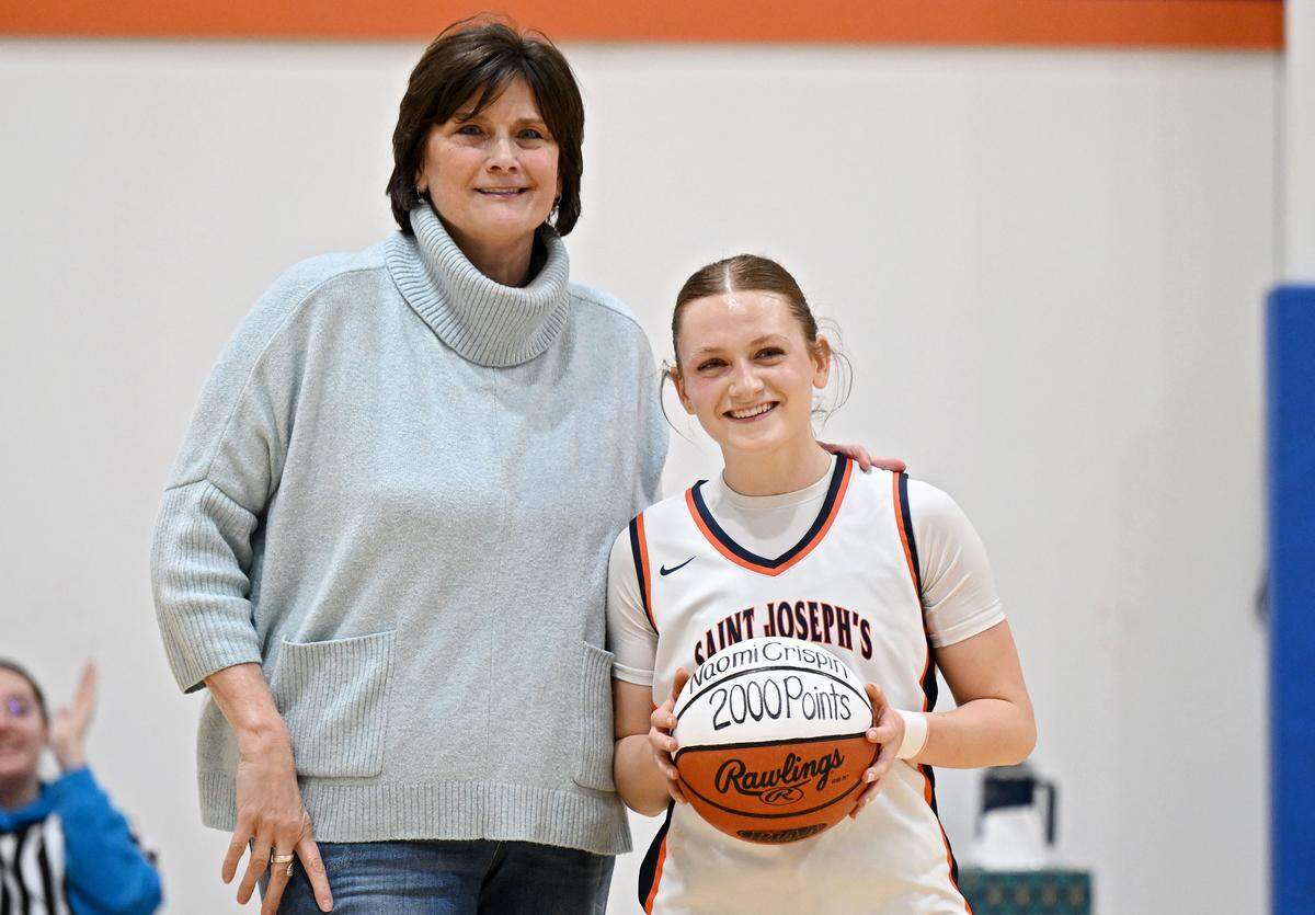 Saint Joseph’s Catholic Academy girls basketball coach Bethany Irwin presented Naomi Crispin with a ball when she hit her 2,000th point during the game against Juniata on Monday, Feb. 9, 2026.