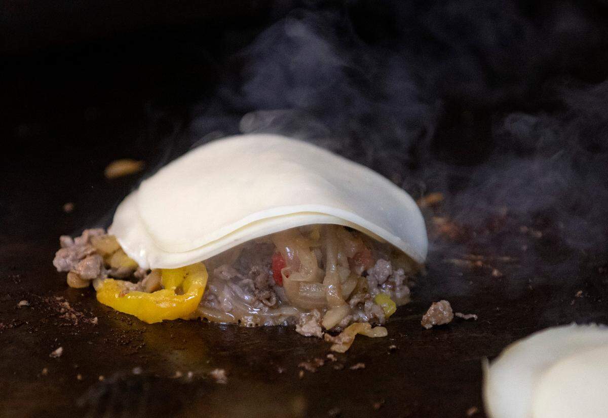 Provolone cheese melts over rib eye and caramelized onions and peppers to go on the Dambach-ery burger, a cheesesteak burger at The Field Burger & Tap on Wednesday, May 31, 2023.