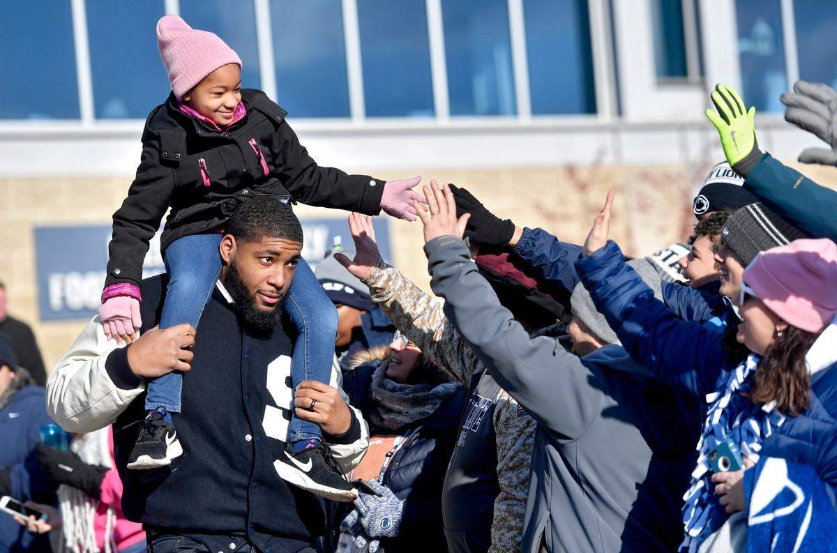 Leah Still high-fives fans from the shoulders of her dad and former Penn State football player Devon Still before the football team arrives for its game against Wisconsin at Beaver Stadium on Nov. 10, 2018. Leah is now cancer free after a battle with neuroblastoma, and Devon isn’t giving up his fight against the disease.