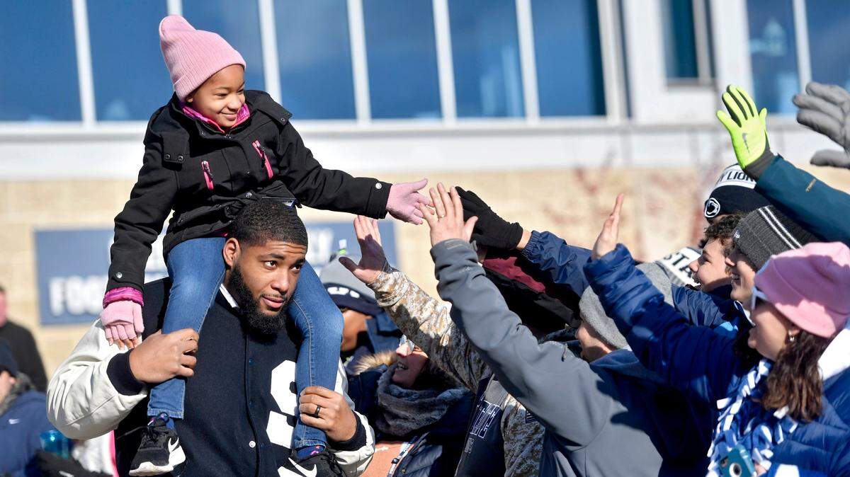 Leah Still high-fives fans from the shoulders of her dad and former Penn State football player Devon Still before the football team arrives for its game against Wisconsin at Beaver Stadium on Nov. 10, 2018. Leah is now cancer free after a battle with neuroblastoma, and Devon isn’t giving up his fight against the disease.