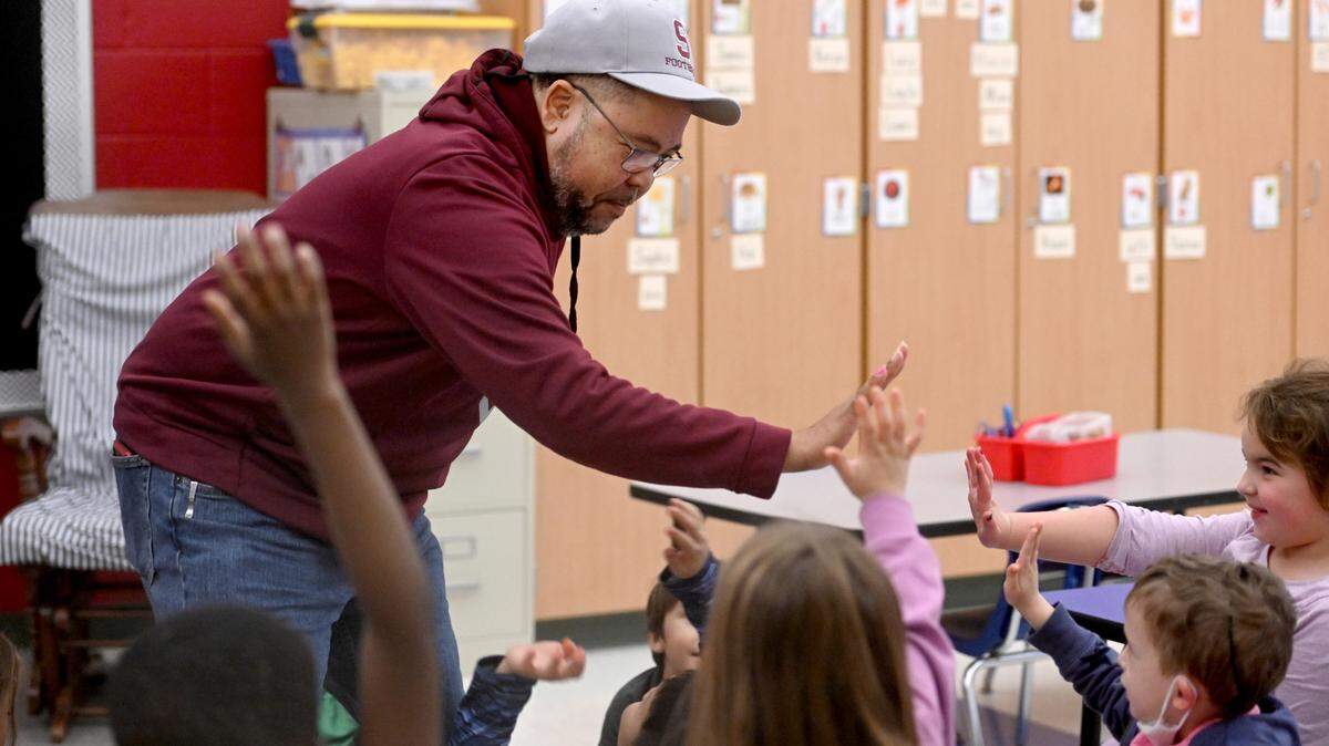 Army veteran Rick Ortiz high-fives kindergarten students Friday after reading them a book and answering several questions at Park Forest Elementary School.