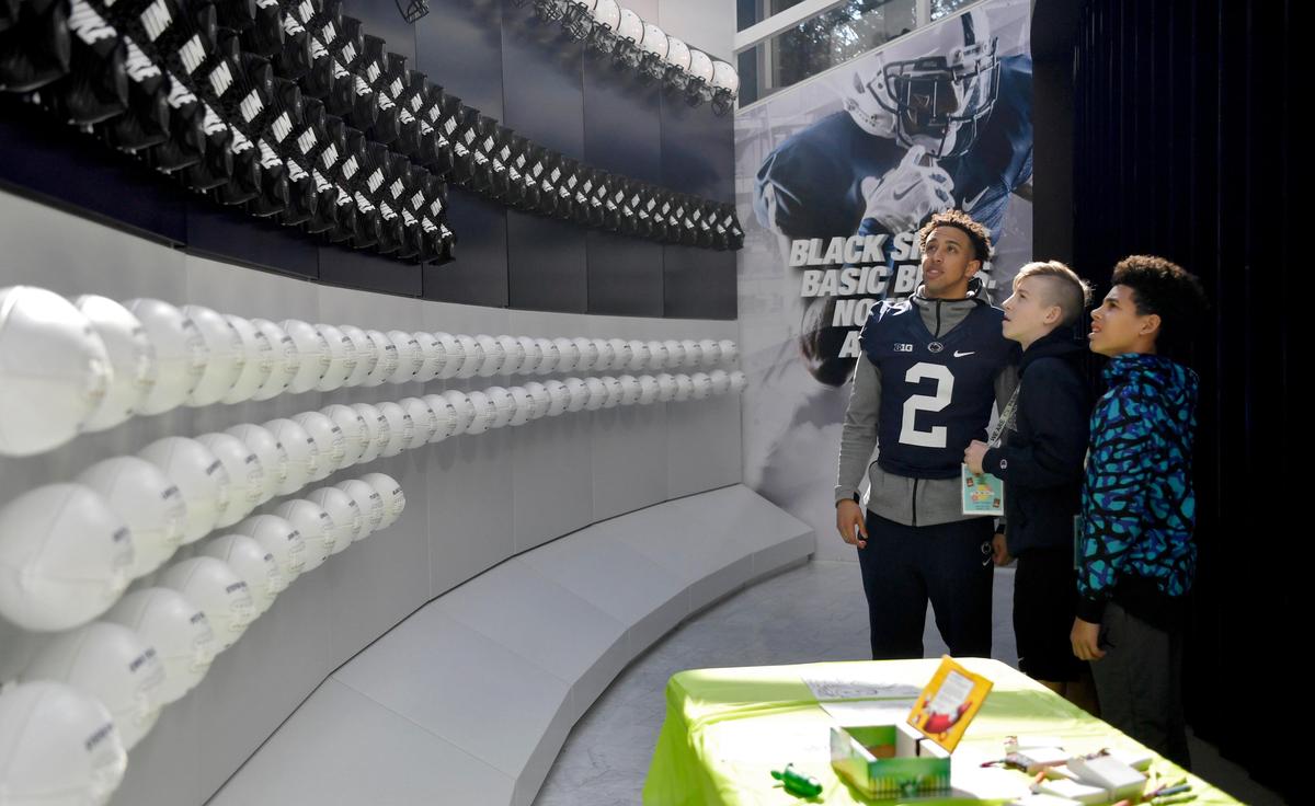 Penn State cornerback Keaton Ellis shows several youngsters one of the awards walls in the Lasch Building on Saturday, Feb. 22, 2020.