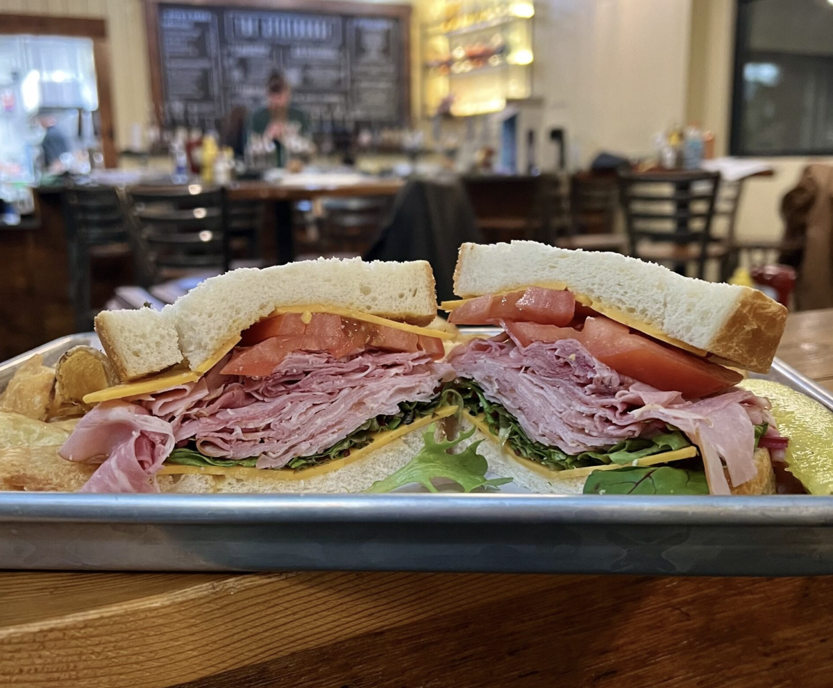 The StillHouse’s Pine Creek honey ham sandwich features shaved honey-baked ham, cheddar cheese, lettuce, tomato and Roger’s Almost Famous mustard, served with chips and pickle spear.