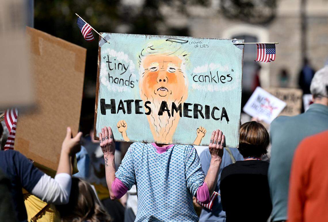 A protester holds a sign as they listen to the speakers at the No Kings anti-Trump rally on Saturday, Oct. 18, 2025. 
