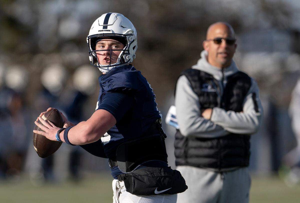 Penn State quarterback Drew Allar makes a pass as coach James Franklin watches during a spring practice on Tuesday, March 21, 2023.