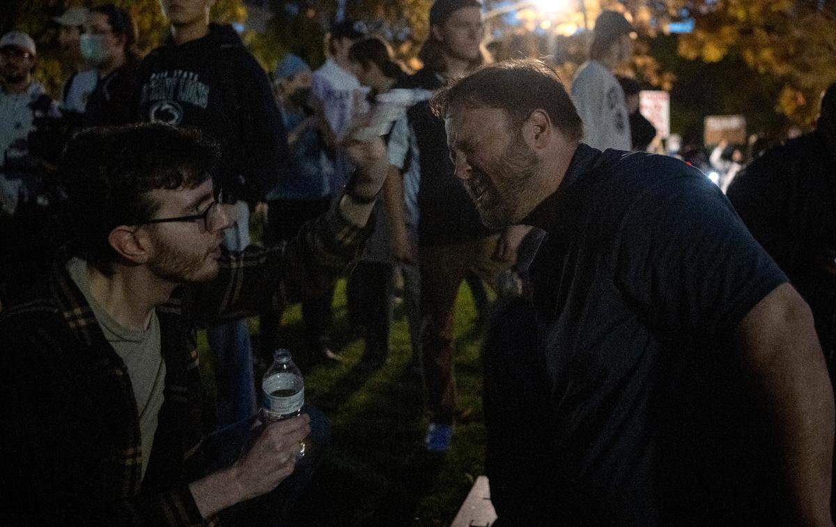 People try to wash their eyes after being hit with a bear deterrent spray outside of the Thomas Building on Monday, Oct. 24, 2022.