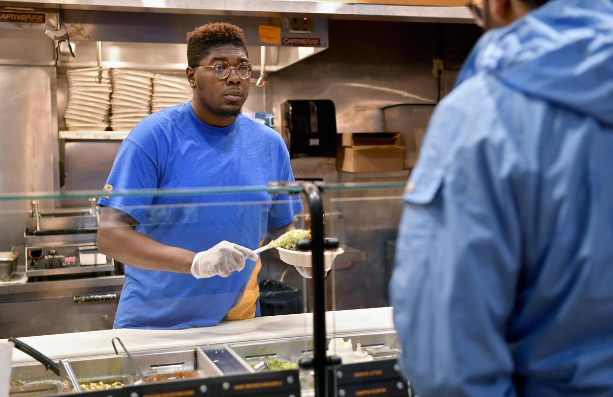 Student Kenny Mack works on an order Tuesday at Qdoba in downtown State College. Many businesses, like Qdoba, have had to cut back their hours and up their wages to attract workers during this labor shortage.