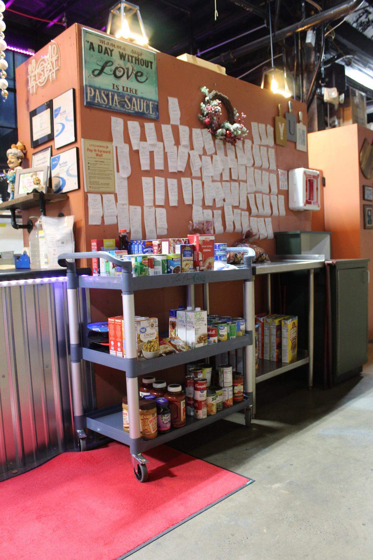 The pay-it-forward wall and miniature food pantry at Little Mamma’s Pizza, located in the Titan Market at 2042 Axemann Road near Bellefonte.