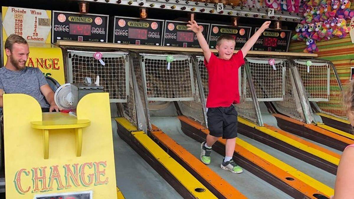 Blake Stoner, an 8-year-old with Down syndrome, celebrates after a successful skee ball game at the Centre County Grange Fair.